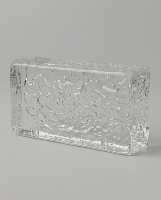 Clear glass block with textured surface on a gray background