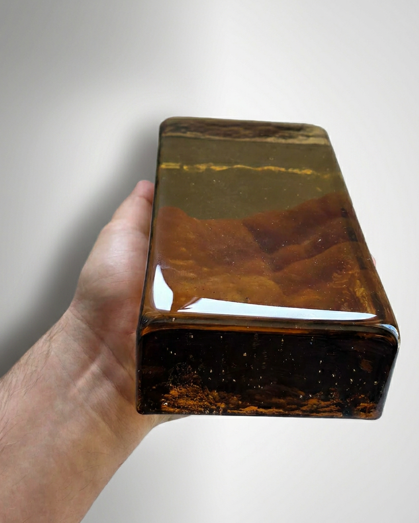 Hand holding a large brown and black stone against a white background