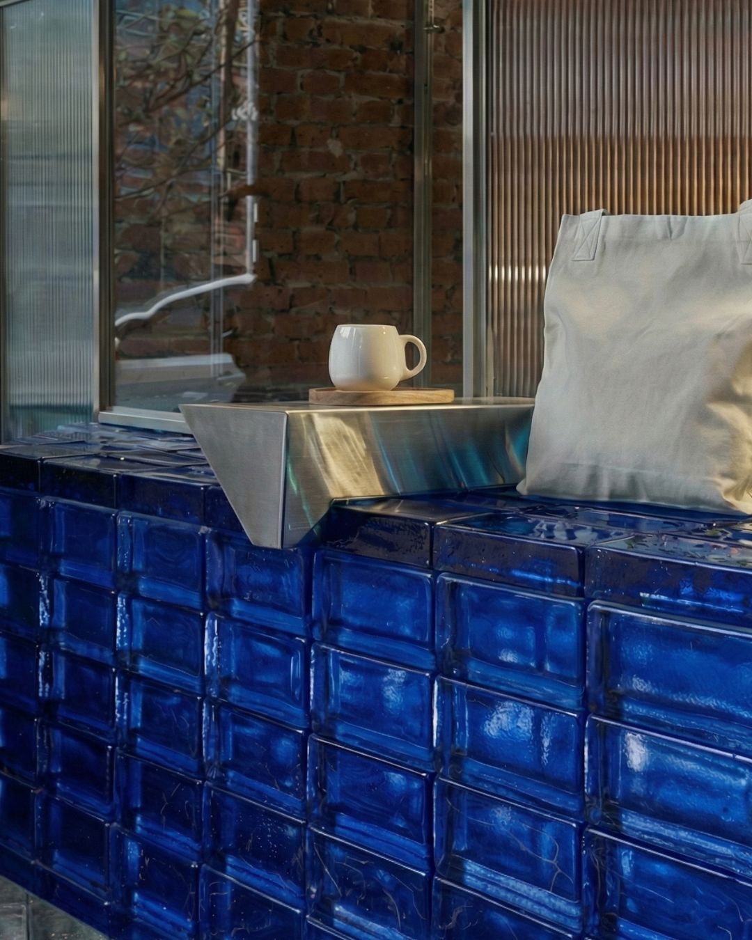 Dark luxury bathroom with glass brick wall partition, bathrobe, and floating vanity